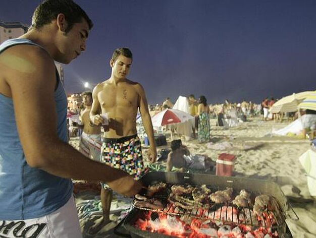 Unos j&oacute;venes preparan la cena en la arena. 

Foto: Lourdes de Vicente