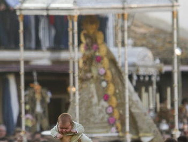 Un hombre se acerca a la virgen del Rocio llevando un bebe para posarlo en su manto.

Foto: Juli&aacute;n P&eacute;rez (EFE)