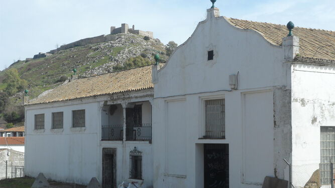 Edificio de la cooperativa San Blas, conocido como la Almazara, con el castillo de Aracena al fondo.