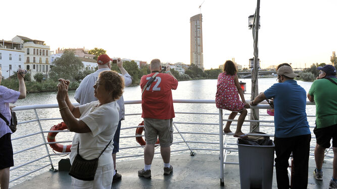 Turistas fotografían la ciudad desde uno de los barcos que recorre a diario el río.