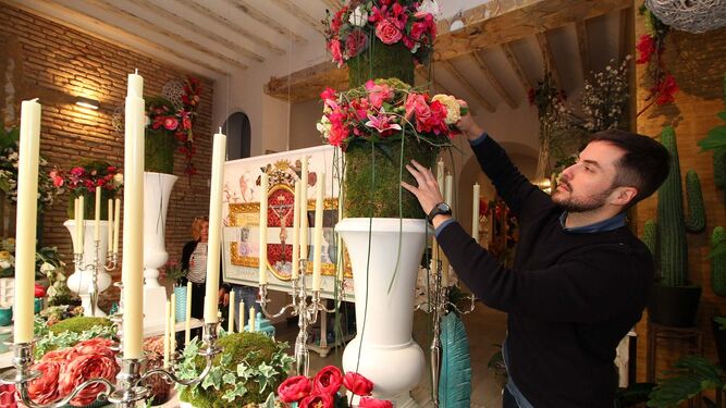 Antonio Rivera prepara un centro de flores para el escaparte en el que tiene el original del cartel de Semana Santa.
