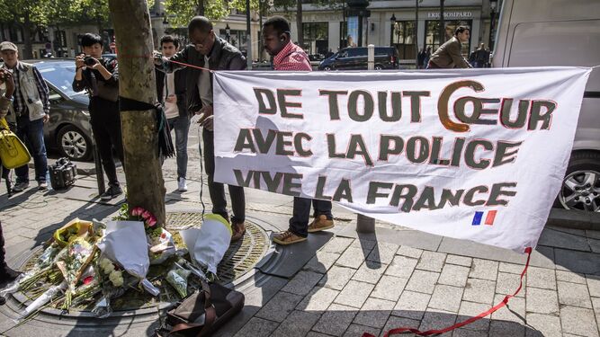 Unas personas colocan un cartel que dice 'De todo corazón con la policía. Viva Francia' donde fue asesinado anoche un policía durante un ataque yihadista de los Campos Elíseos.