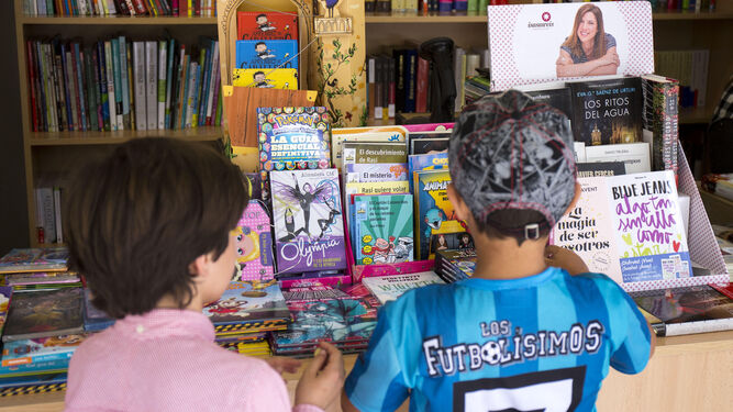 Dos niños revisan la oferta infantil de uno de los estands de la Feria del Libro en la Plaza de las Monjas.
