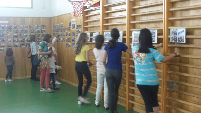 Alumnas y madres miran atentamente las fotografías de la exposición.