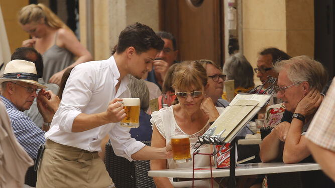 Un camarero sirve una cerveza en la terraza de un bar.