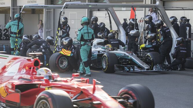 Sebastian Vettel pasa junto al 'box' de Mercedes mientras los mecánicos de la escudería germana cambian las ruedas del monoplaza de Lewis Hamilton.