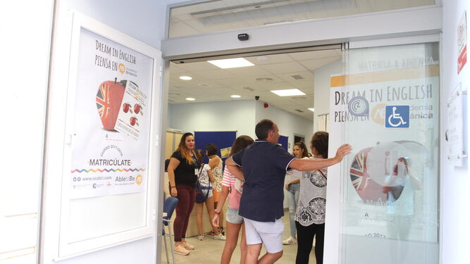 Varias personas esperan para ser atendidas en la Academia Británica de Huelva.