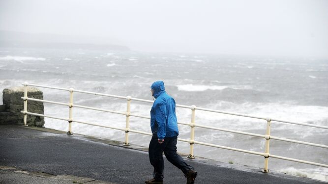 Un hombre camina junto al fuerte oleaje en el Condado de Clare (Irlanda).
