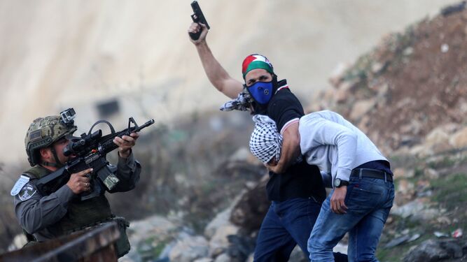 Un policía israelí ataviado con un pañuelo con la bandera palestina deteniendo ayer a un manifestante en Ramala.