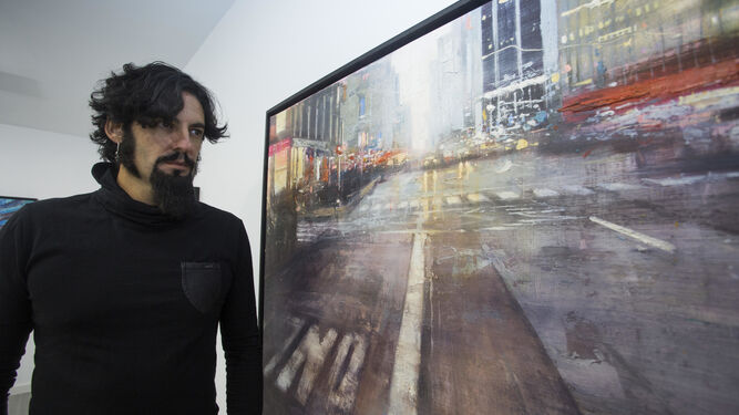 El creador posa junto a una de sus pinturas, en que la recrea la magnética nocturnidad de Manhattan.