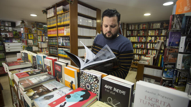 Un dependiente hojea un libro en Saltés (calle Ciudad de Aracena), librería de referencia en la capital onubense desde hace cuatro décadas.