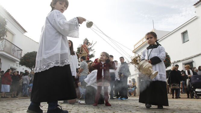 Niños vestidos de monaguillos echan incienso al paso de la imagen de San Sebastián por las calles de Cartaya.
