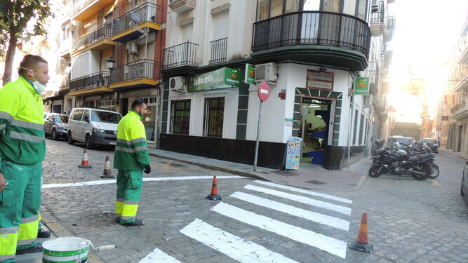 Dos operarios proceden al repintado de un paso de peatones en la calle Fernando el Católico.
