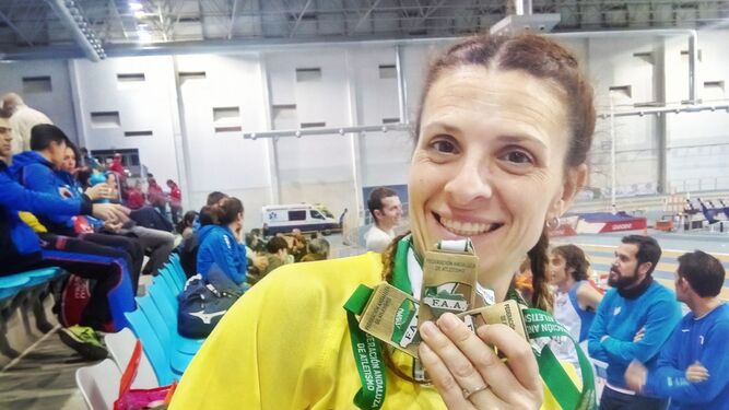 Elena Cobos García muestra sonriente sus tres medallas de oro.