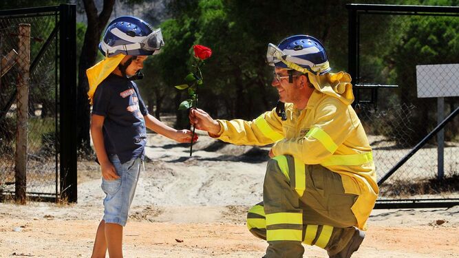 Un niño entrega una rosa a un bombero del Infoca en Mazagón el día siguiente del incendio en el entorno de Doñana.