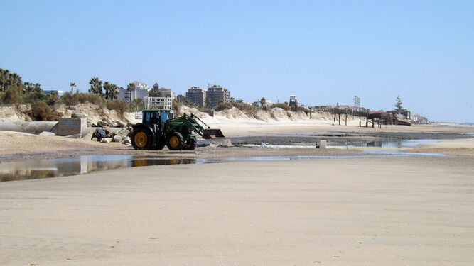 Una máquina excavadora en la playa de Islantilla.