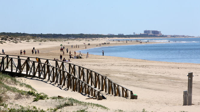 Visitantes disfrutan de un paseo por una de las playas onubenses.