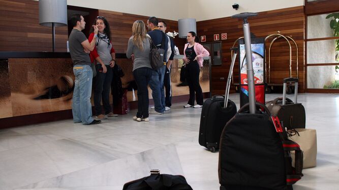 Varios turistas aguardan en la recepción de un hotel de la costa de Huelva.