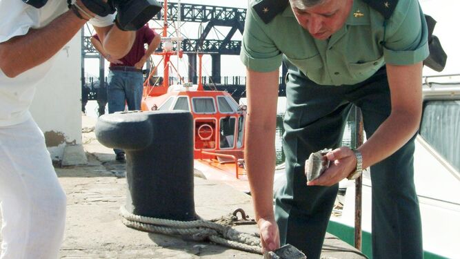 Un agente de la Guardia Civil muestra una placa de hachís incautada en un alijo en Huelva.