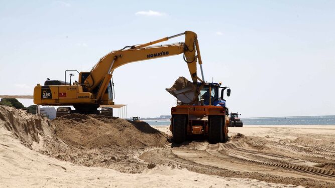 La excavadora carga en los remolques de los tractores arena para ser redistribuida.