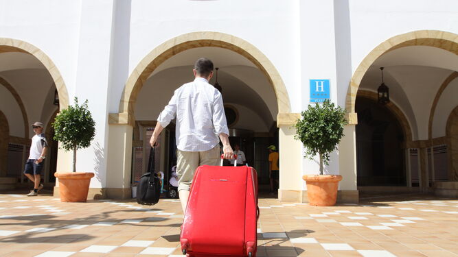 Un cliente se dispone a entrar con su maleta en un establecimiento hotelero.