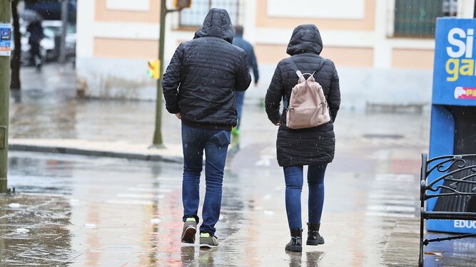 Una pareja camina bajo la lluvia.
