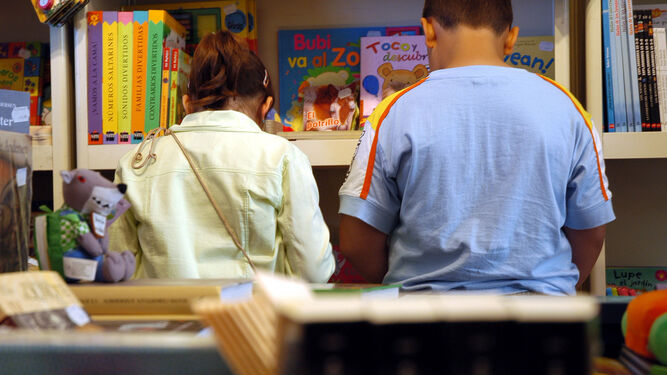 Niños en una biblioteca con libros y cuentos en las manos.