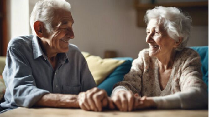 Dos personas mayores cogidas de la mano sonríen mientras le toman una fotografía.