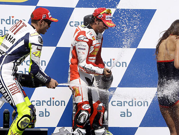 Valentino Rossi y Toni El&iacute;as roc&iacute;an con champ&aacute;n a una de las azafatas en el podio de MotoGP.

Foto: Reuters