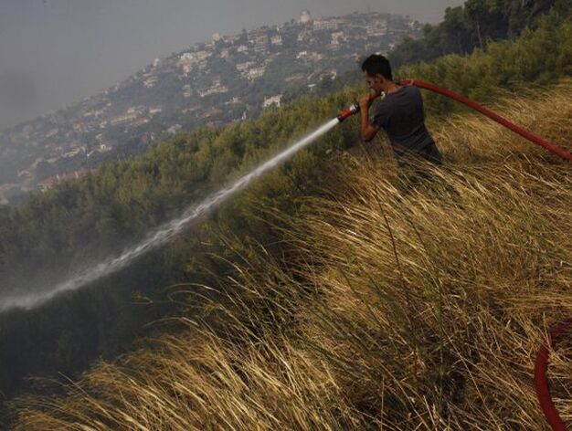 Un voluntario combate las llamas en la poblaci&oacute;n griega de Pedeli, a 20 kil&oacute;metros de Atenas.

Foto: Efe