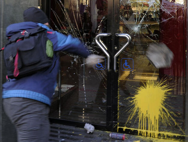Un joven lanza piedras y bolas de pintura contra un banco.

Foto: Afp