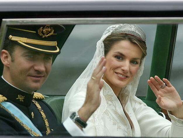 Los reci&eacute;n casados saludan al p&uacute;blico desde el coche en su paseo por las calles de Madrid. / Efe