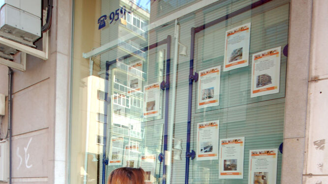 Una mujer observa las ofertas de venta de pisos de una inmobiliaria.