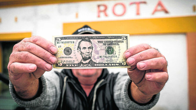 Un gorrilla posa ante la antigua estación de tren de Rota con un billete de dólar con la efigie del primer presidente republicano, Abraham Lincoln.
