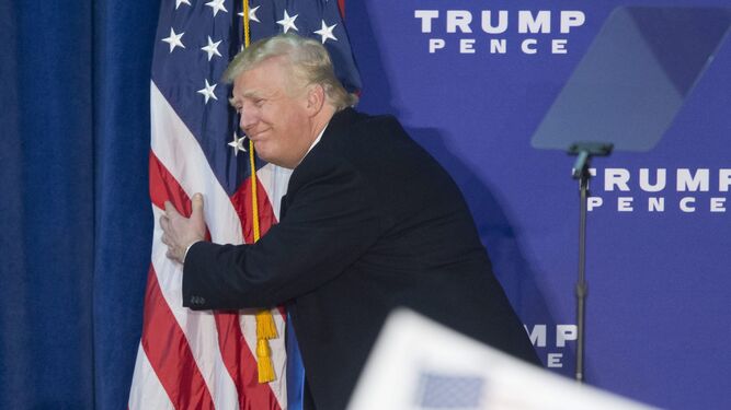 Donald Trump abraza la bandera estadounidense.