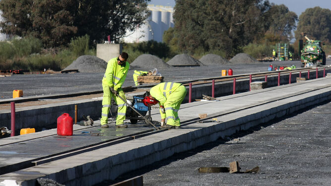 Dos operarios trabajan en la construcción de las líneas de ferrocarril en el Muelle Sur del Puerto de Huelva.