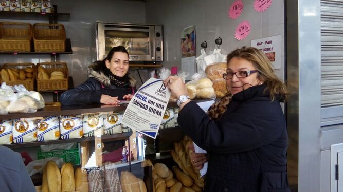 Paloma Hergueta entrega un cartel a una tendera del Mercado del Carmen.