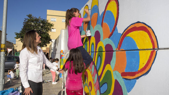 Dos niñas pintan uno de los tramos del muro.