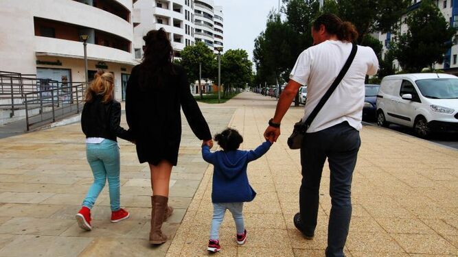 Marco lleva de la mano a su pequeña de acogida, acompañado por la educadora Mónica Vázquez y por su hija Chiara.
