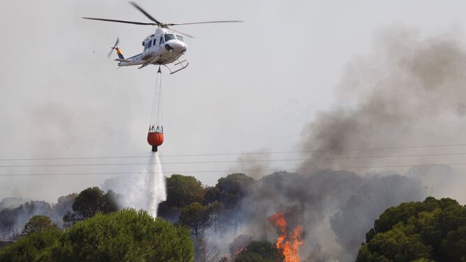Un helicóptero suelta agua en la zona afecatda por las llamas.