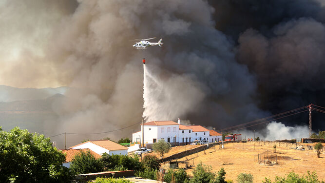 Un helicóptero arroja agua sobre las llamas, muy cerca de las viviendas.