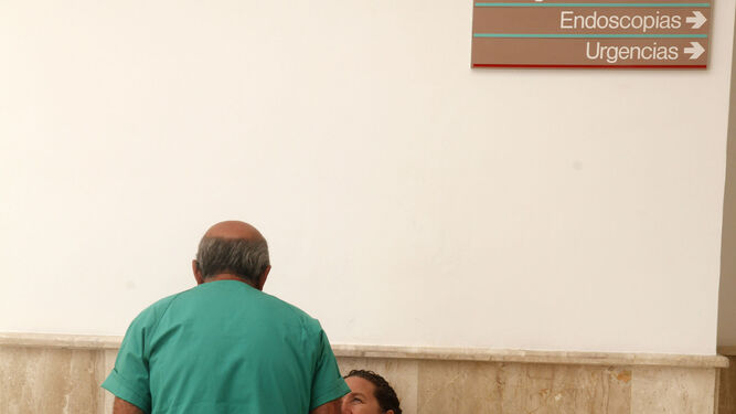 Un sanitario charla con dos personas que esperan.