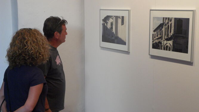 Algunos visitantes observan dos de las fotografías que se exhiben.
