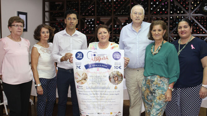 Charo Venegas, entre Juan Capela y Manuel Catalán, con el cartel del espectáculo 'Noche alosnera' junto a mujeres de la localidad.