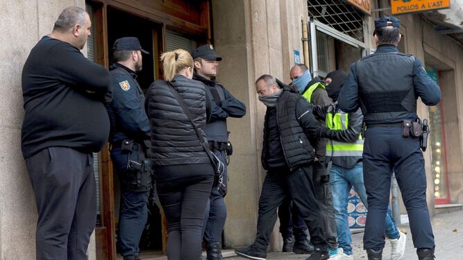 Varios agentes custodian ayer a un detenido durante uno de los registros en Barcelona.