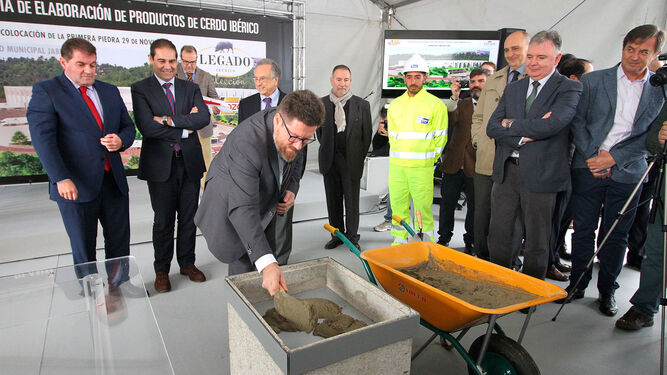 El consejero de Agricultura, Pesca y Desarrollo Rural, Rodrigo Sánchez Haro, manipula cemento en la colocación de la primera piedra.