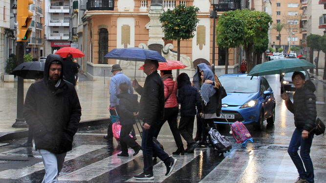 Trasnseúntes bajo la lluvia en la calle Puerto de la capital.