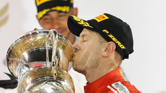 Vettel besa el trofeo con Hamilton al fondo.
