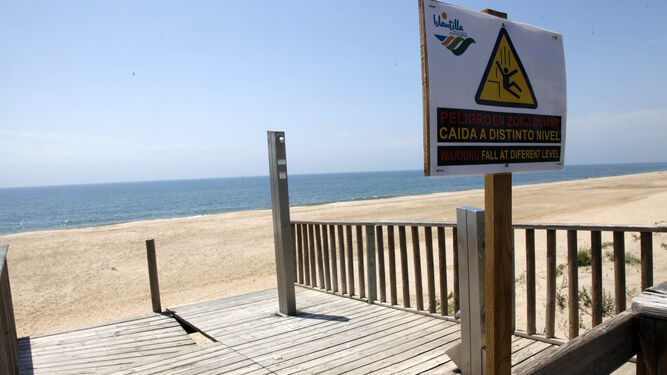 Aviso de peligro de una pasarela, dañada por el oleaje del mar.