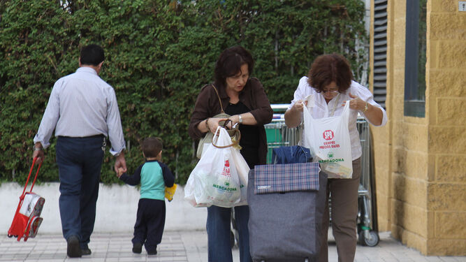 Mujeres con bolsas de plástico a la salida de un supermercado.